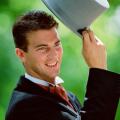 Lifestyle. Wedding. Man outdoors raising his top hat.