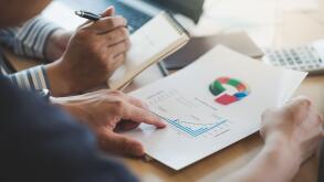 Businessman hand holding report document in office meeting room with business discussion and brainstorm atmosphere in blurry background.