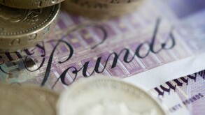 Twenty pound sterling notes and one pound coins are set up for a photograph