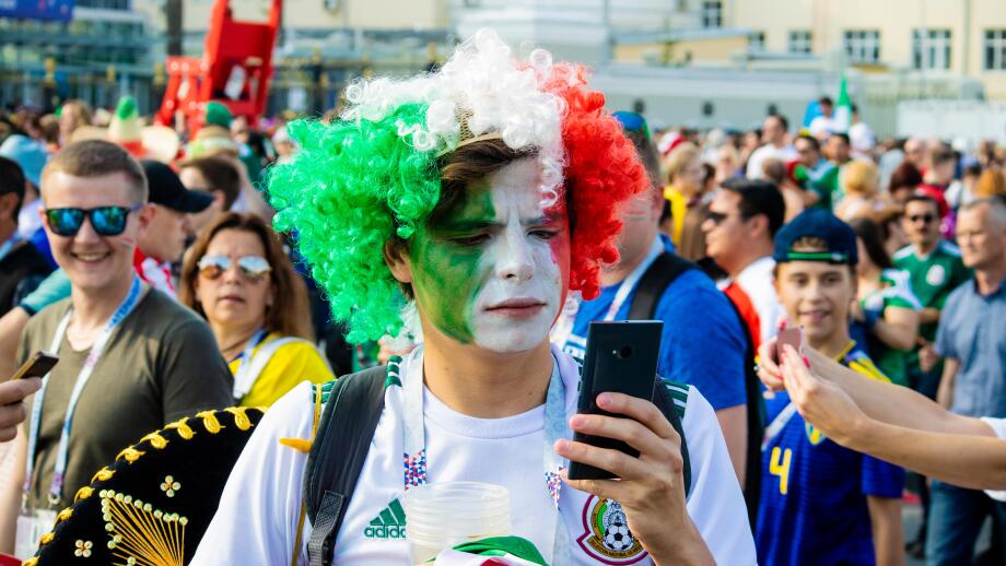 Serious male Mexican football fan with frizzy green, white and red wig checks mobile phone - FIFA World Cup Russia 2018 Mexico v Sweden, Ekaterinburg
