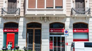 Tortosa, Spain - May 13, 2022: Facade and logo of the Banco Santander with people at the ATM in Tortosa, Catalonia, Spain