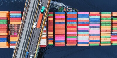 Container ship passes beneath a suspension bridge road highway car supply chain.jpg