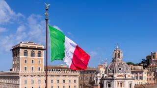 The Italian flag seen in front of the Church of Santa Maria di Loreto al Foro Traiano on the right, Rome, Lazio, Italy