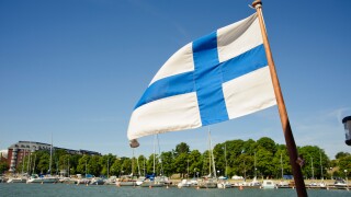 The Finnish flag flies from a boat shuttling between Unisaari island and the Merisatama quayside, Helsinki Finland