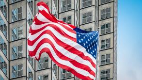 American flag in front of skyscraper.