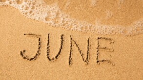 June - written in sand on beach texture, soft wave of the sea