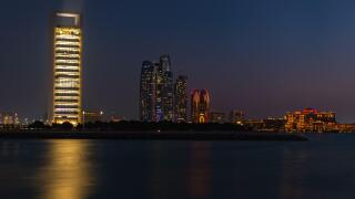 A picture of the Etihad Towers, the Abu Dhabi National Oil Company Headquarters and the Emirates Palace Mandarin Oriental Hotel at night.