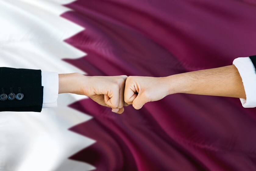 Qatar agreement concept. Man and woman fist bumping on national flag to show cooperation. Peace and teamwork theme.