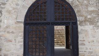 Black iron open gate in a stone wall, entrance into a medieval fortress