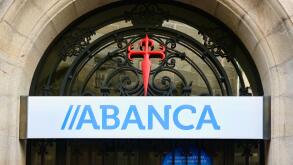 Cross of Saint James and Abanca Sign over the entrance to a bank branch in the historic city centre of Santiago de Compostela Galicia Spain