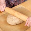 Woman rolling ball of bread dough with a rolling pin to flatten it, prior to forming it into a loaf. (MR)