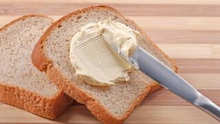 A knife spreading butter on wheat bread