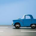 Side view of a blue toy car on a blue background and on an asphalt road.