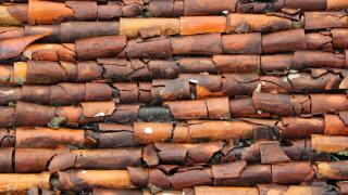 Rustic and broken clay roof tiles on a house