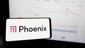 Person holding mobile phone with logo of British insurance company Phoenix Group Holdings plc in front of web page. Focus on phone display.
