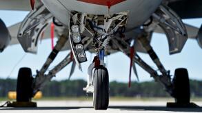 Military aircraft detail with landing gear and engine cover on a runway