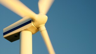 Wind turbine rotors with blue sky generating electricity on wind farm at Workington, Cumbria, England, UK. Warm evening light