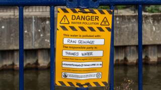 Protest sign reading Danger water pollution, this water is polluted with raw sewage. The responsible party is Thames Water. River Wey, Guildford, UK