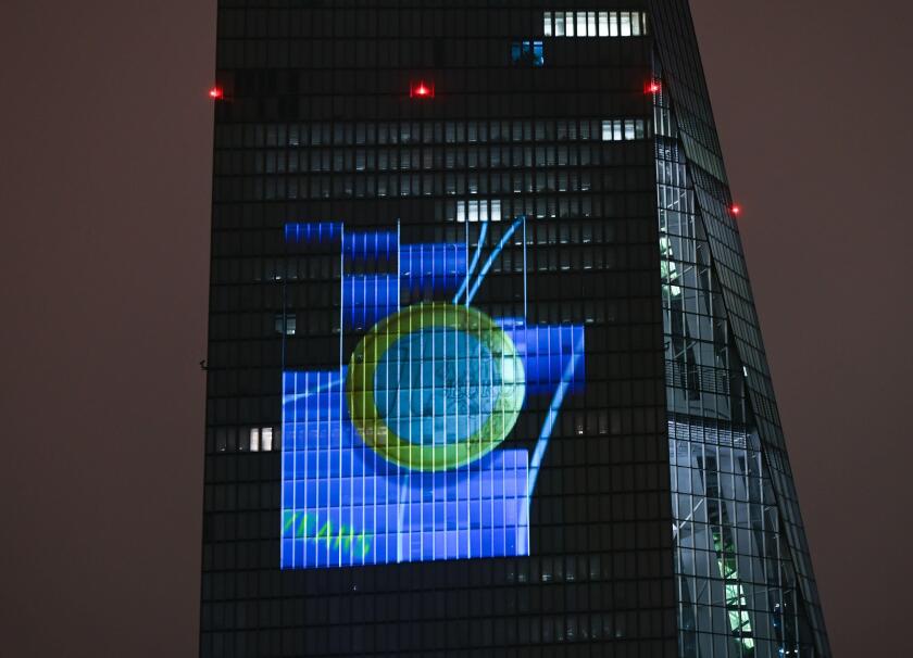 05 January 2022, Hessen, Frankfurt/Main: To mark the introduction of euro cash 20 years ago, a euro coin is projected onto the south facade of the European Central Bank (ECB) headquarters in Frankfurt's East End. On the New Year's night of January 1, 2002