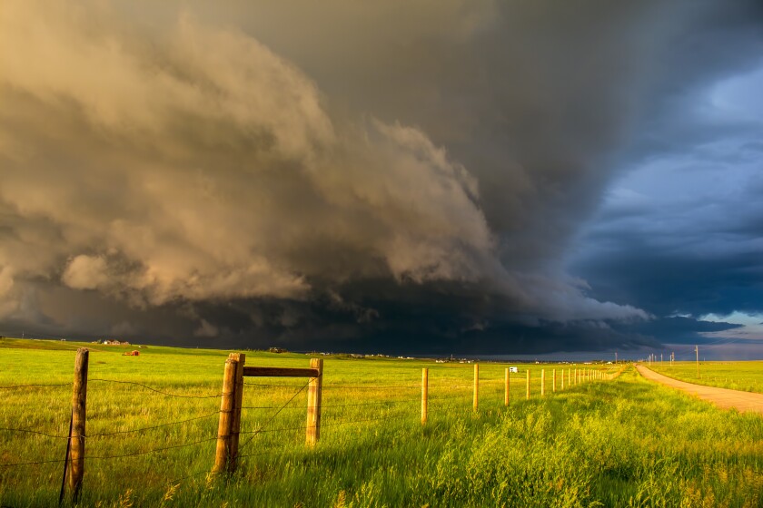 A dark shelf cloud and storm approach as the sun shines brightly