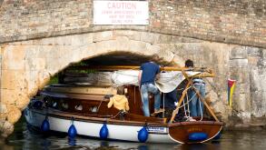 Small yacht carefully navigating the low bridge at Potter Heigham, on the Norfolk Broads, England UK
