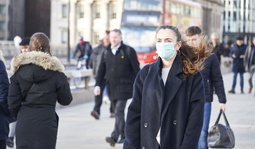 Young woman wearing face mask while walking in the streets of London