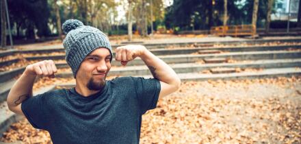 Man flexing muscles while standing in park during autumn
