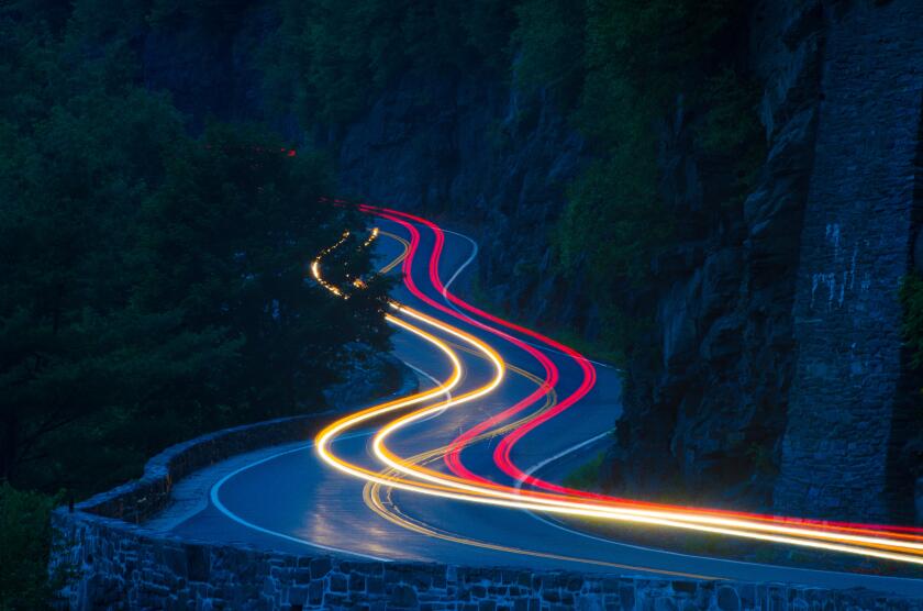 Hawk's Nest mountain road, New York State Route 97, at night. Streaks of red and yellow lights follow the curving road.