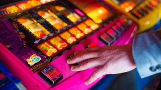 a man's hand on a fruit machine gambling