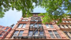 Looking up at an old building with fire escape, New York City, USA.