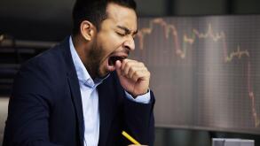 Tired businessman on the stock market, trading during a financial crisis. Yawning trader in a bear market, looking at stocks crashing. Market crash