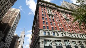 the burton building with mixed design architecture architectural details looking up 5th avenue with view of the empire state building New York City US