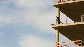 Construction worker fitting safety rails to s partly built office block, Dusseldorf, Germany.