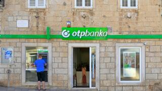 A tourist using an ATM outside an Otp Banka in Korcula Town, Korcula Island, Croatia, Dalmatia, Dalmatian Coast, Europe.