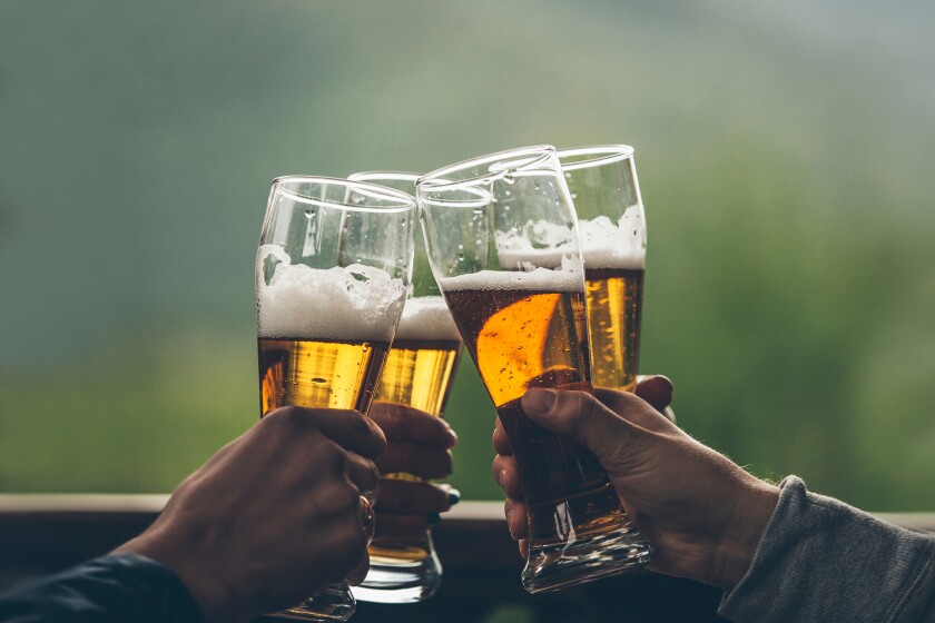 Beer with foam light tall boys in the hands of friends raising a toast closeup