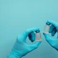 Doctor or nurse wearing blue surgical gloves holding a double vaccine dose