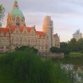 Rear view of Hannover City Hall with a reflective pond and surrounding park landscape.
