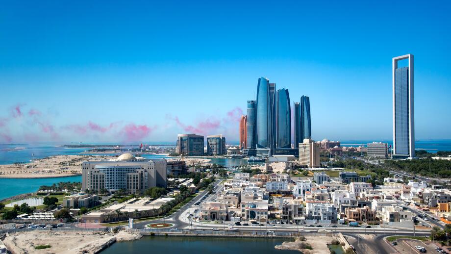 Abu Dhabi skyline with air show colors in the sky and view of the downtown modern buildings of the UAE capito