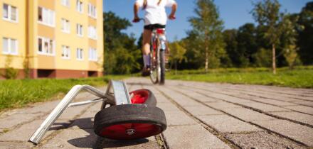 Girl on bicycle leaving her training wheels behind