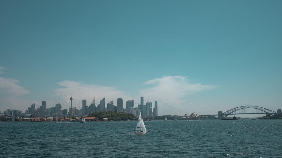 Wide angle view of the Sydney Harbour skyline featuring the CBD, Sydney Opera House, and Harbour Bridge with sailboats in the foreground.
