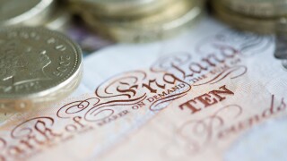Ten pound sterling notes and one pound coins are set up for a photograph