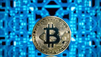 Standing golden bitcoin crypto currency blockchain coin against a blue reflective circuit board background
