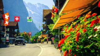Picturesque cozy alpine village with shops and rustic wooden houses. Cute mountain village with flowery street and high mountains in background, Laute