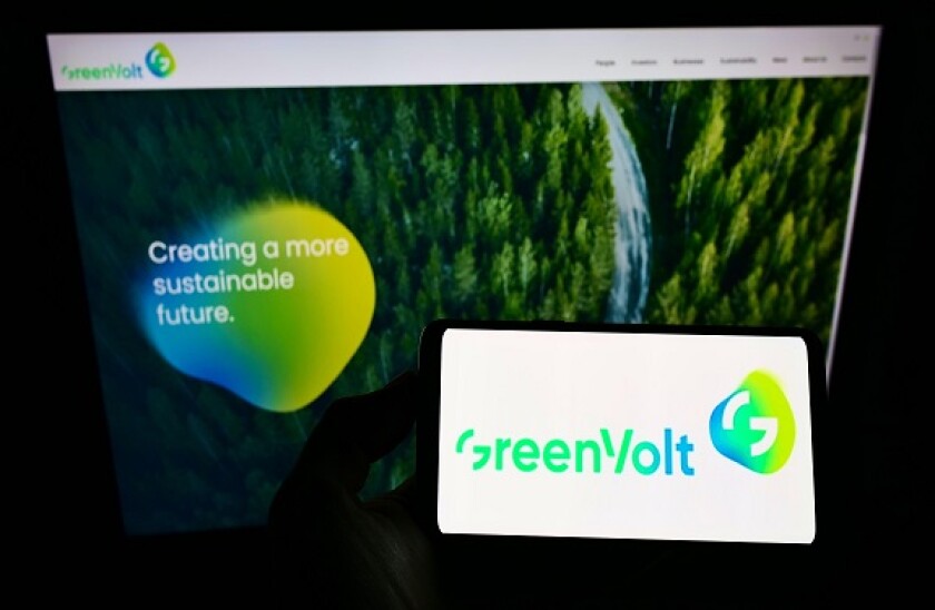 Person holding smartphone with logo of energy company Greenvolt Energias Renovaveis SA on screen in front of website. Focus on phone display.