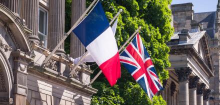 French flag and Union Jack flying side by side on flagpoles outside a historic building in Edinburgh, UK. Might depict European travel or allied natio