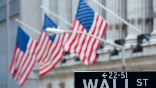 Detail of Wall Street sign with flags on Stock Exchange building to rear Manhattan New York City