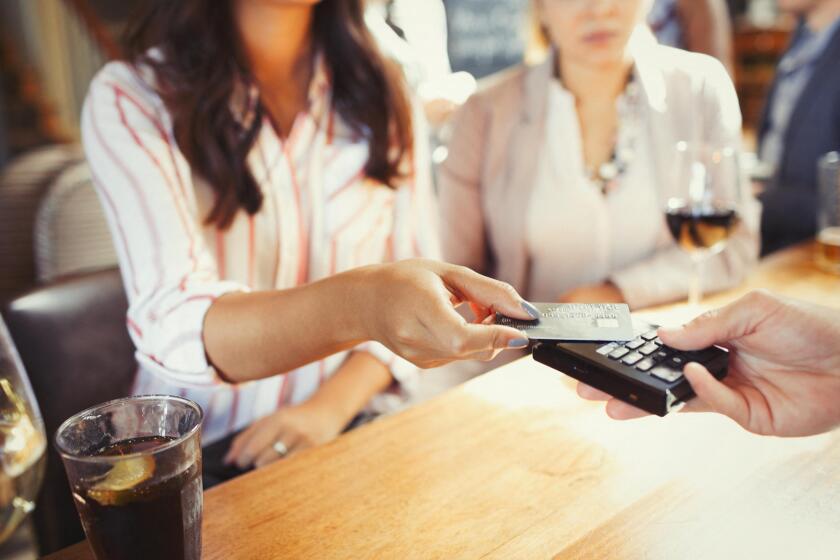 Woman paying bartender with credit card contactless payment at bar