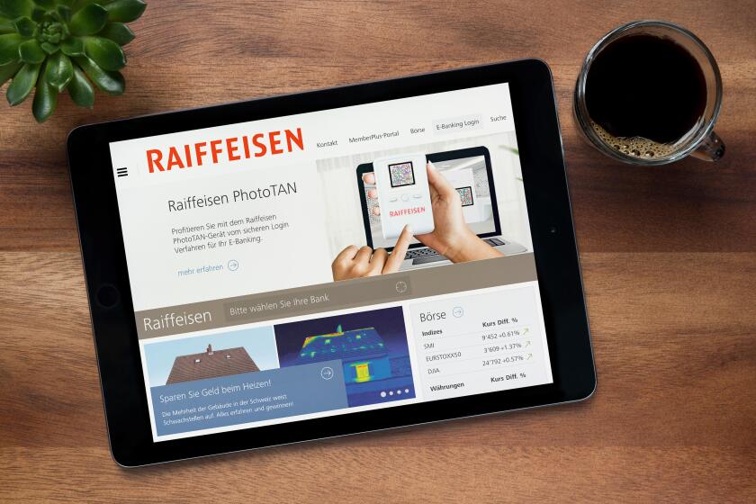 The website of the Swiss bank, Raiffeisen, is seen on an iPad tablet, resting on a wooden (Editorial use only).