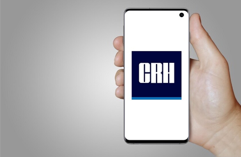 Logo of public company CRH plc displayed on a smartphone. Grey background. Credit: PIXDUCE