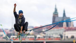a tightrope walker on slack line above the Vltava river with background of panorama of Prague Castle, Czech republic